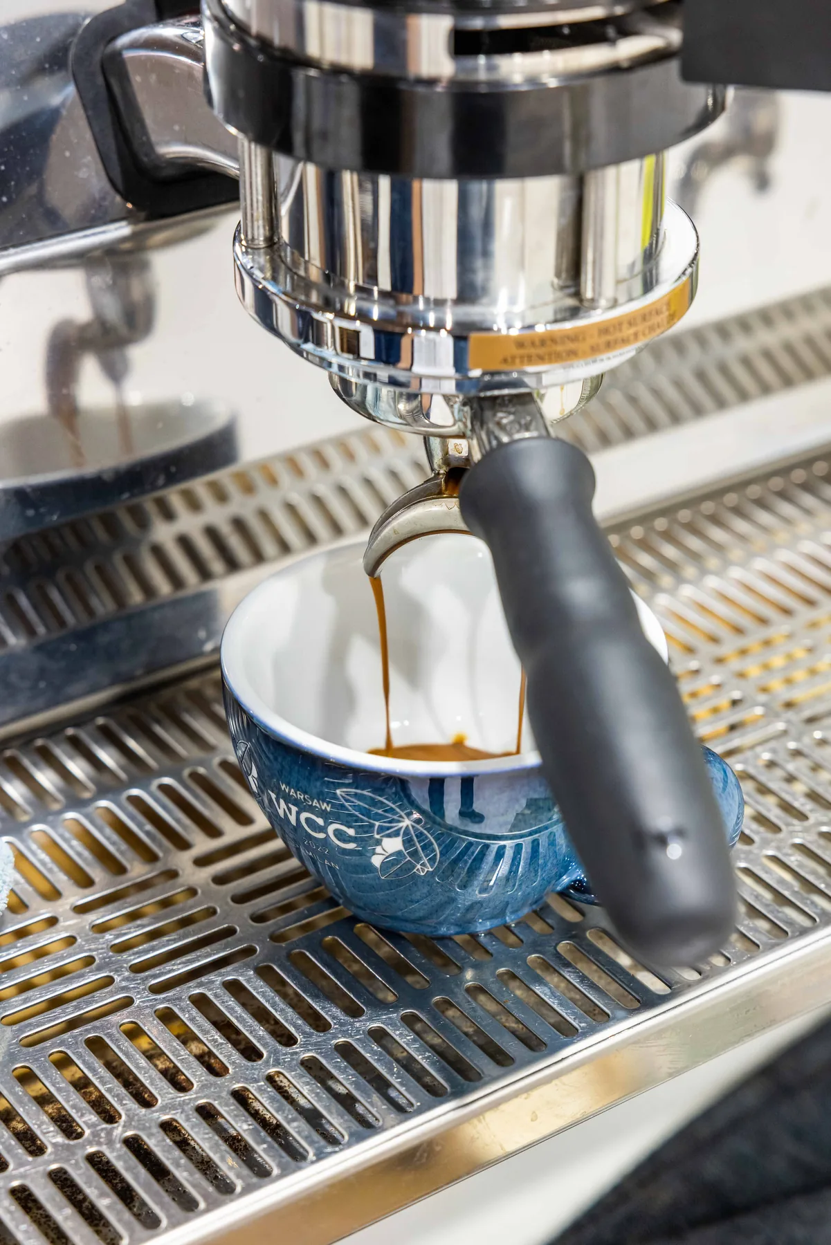 Espresso in estrazione: il caffè scende dal portafiltro in una tazza di ceramica